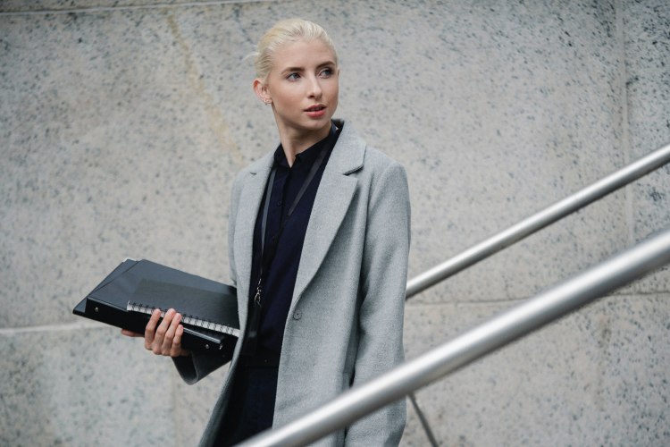 Vrouw grijze jas met folders in hand
