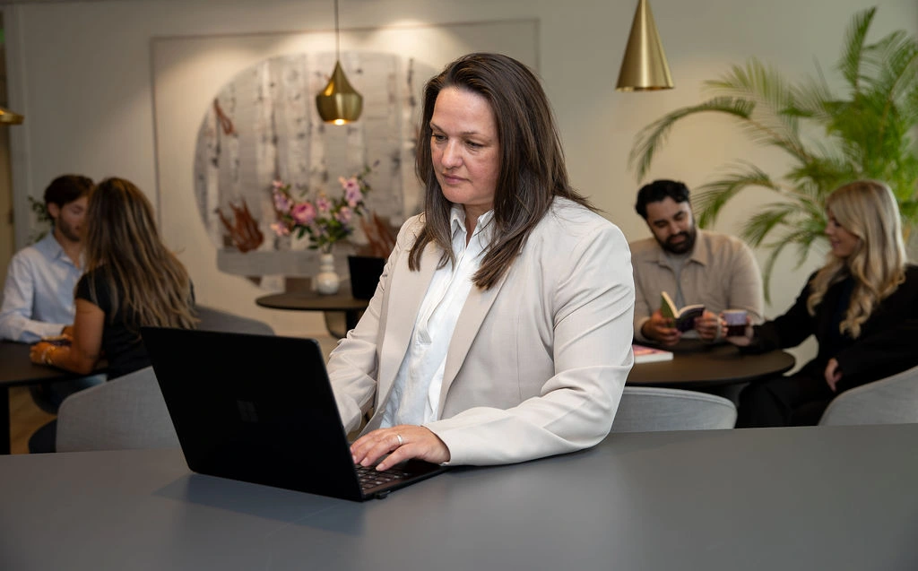 Vrouw grijze jas achter de laptop